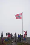 Vikebygd: Flaggheising på Trodlanibbo i noko skodda og skya vêr. Ein god gjeng starta kl. 05.30 nede i Vik og var oppe etter halvannan time. Reidar Winterhus (71) var eldste deltakar på turen og Alfinn Sjo Bjerga (7) den yngste. Alfinn og Askev Winterhus Julsrud (10) heiste flagget.Foto: Roald Årvik