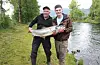 God stemning ved elvebreidda. Veteranen Kjell Harald Hardeland med laksen på elleve kilo han fiska like nedafor Enge bru, med god assistanse av barnebarnet Thomas Lien.Foto: Arne Frøkedal